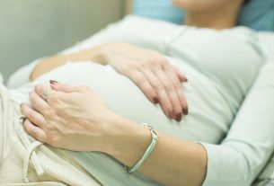 Cropped shot of a pregnant woman keeping hands on the stomach, closeup filtered shot