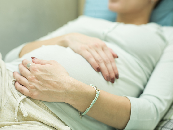 Cropped shot of a pregnant woman keeping hands on the stomach, closeup filtered shot